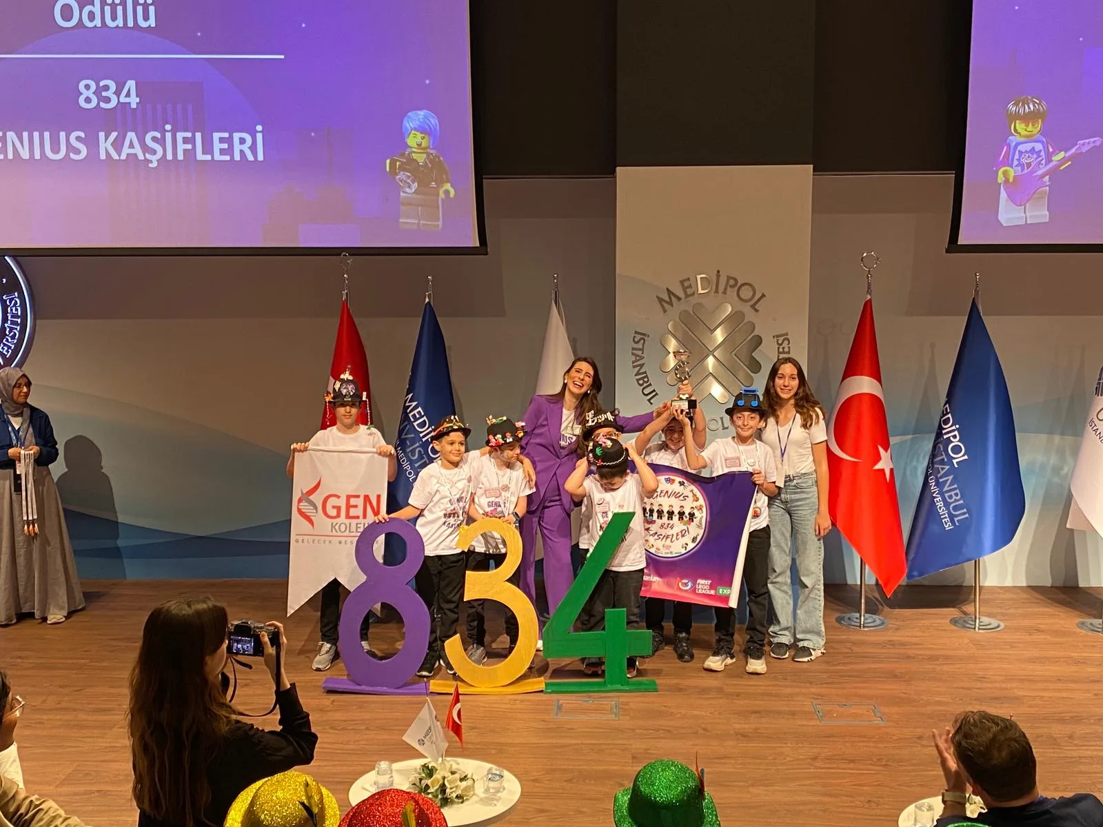 FIRST LEGO League ödül töreninde sahnede takım numarasıyla poz veren GEN Koleji öğrencileri